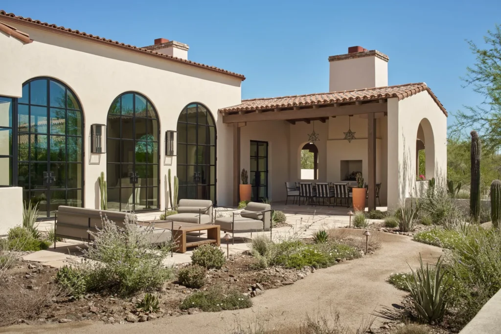 Spanish Colonial courtyard patio with arched steel glass doors, outdoor dining loggia, and desert landscaping by Spiral Architects in Paradise Valley, Arizona.