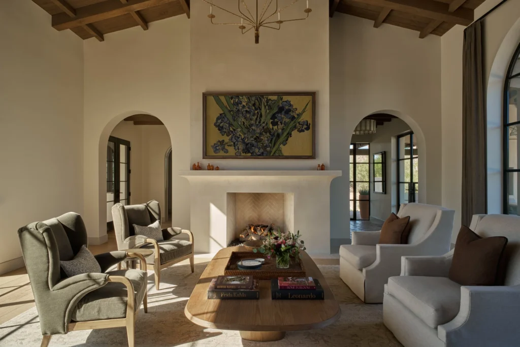 Formal living room centered on smooth plaster fireplace with framed artwork and symmetrical arched corridors in Paradise Valley.